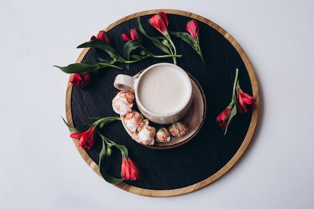 Xícara de cacau e flores na mesa de madeira escura no café