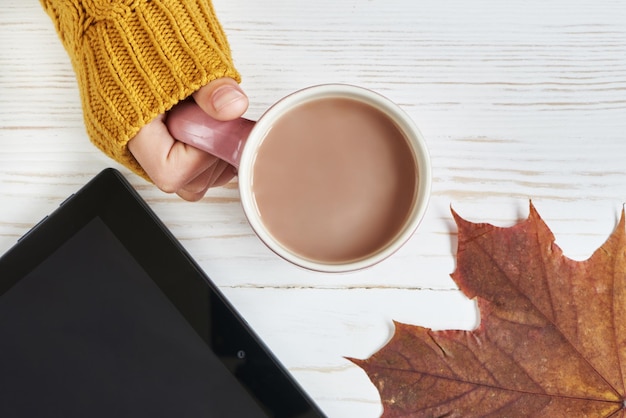 Foto xícara de cacau e mão de mulher folhas de outono tablet pc