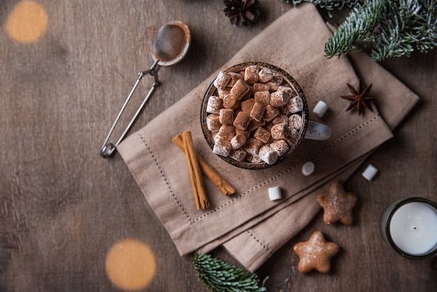 xícara de cacau e marshmallow com pão de mel e canela em fundo madeira