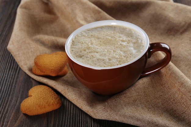 Xícara de cacau quente com biscoitos em forma de coração em guardanapo de algodão close-up