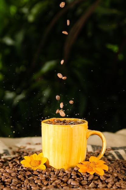 xícara de café amarela com grãos de café na mesa com fundo natural