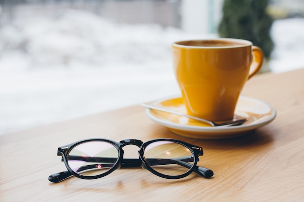 Xícara de café amarelo em cima da mesa e copos