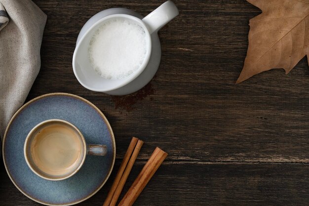 Xícara de café azul com jarro de leite Canela e folha de outono