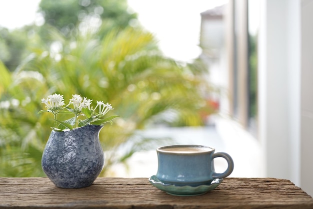Xícara de café azul e flor branca em um vaso azul