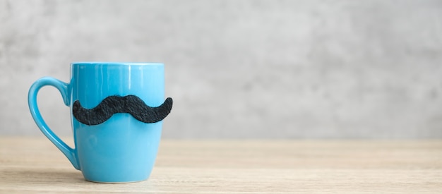 Xícara de café azul ou caneca de chá com decoração de bigode preto na mesa. Espaço de cópia em branco para texto. Novembro azul, feliz dia dos pais e conceito do dia internacional dos homens