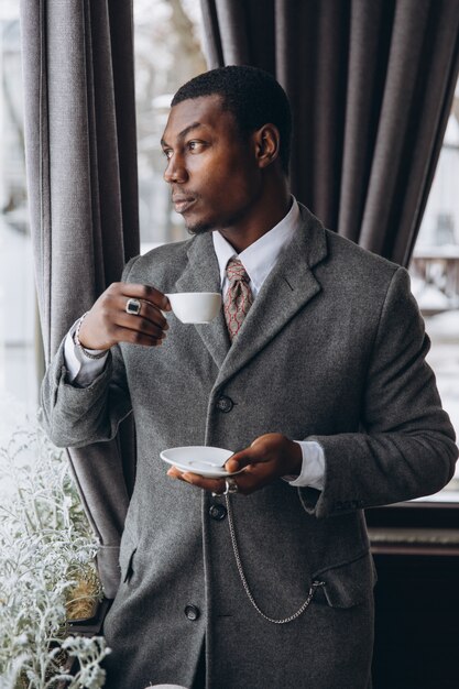 Xícara de café bebendo do homem de negócios afro-americano moderno no restaurante.