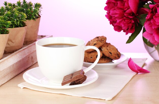 Xícara de café biscoitos chocolate e flores na mesa no café