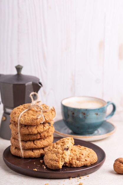 Xícara de café, biscoitos de aveia, cafeteira