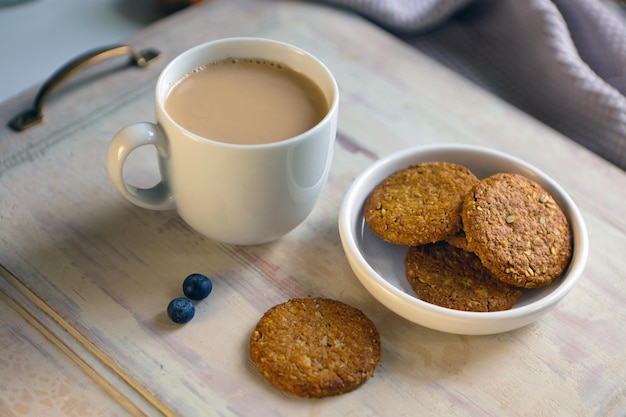 Xícara de café branca com amaretti em fundo cinza claro com caneca de café de aroma de mesa de madeira