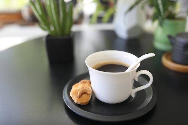 Xícara de café branca e biscoito na mesa preta