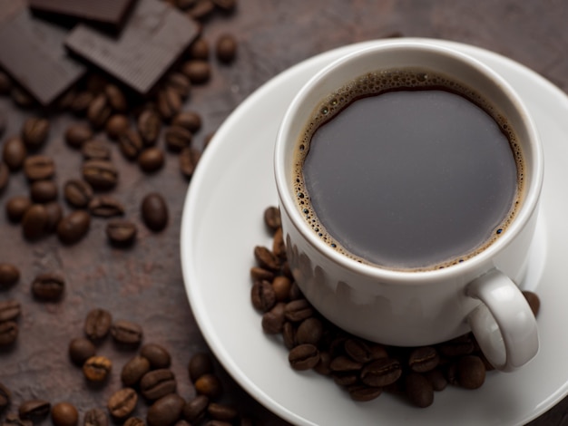 Xícara de café branca e chocolate amargo no fundo de concreto