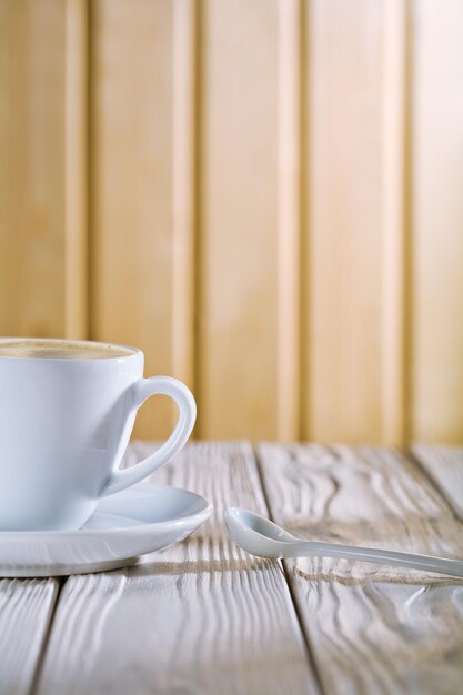 Xícara de café branca e colher na mesa velha