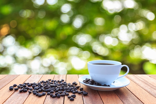 Xícara de café branca e grãos de café na mesa de madeira