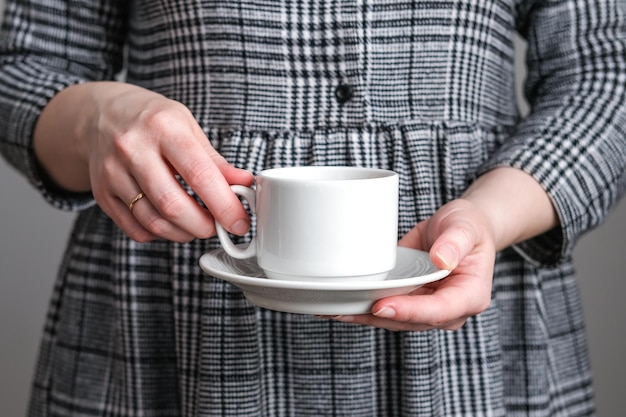 Foto xícara de café branca e pires em mãos femininas maquete para design