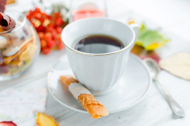 Xícara de café branca e rolos de couro de frutas e batatas fritas no café da manhã