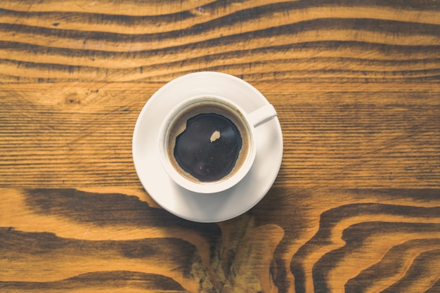 Xícara de café branca em uma mesa de madeira