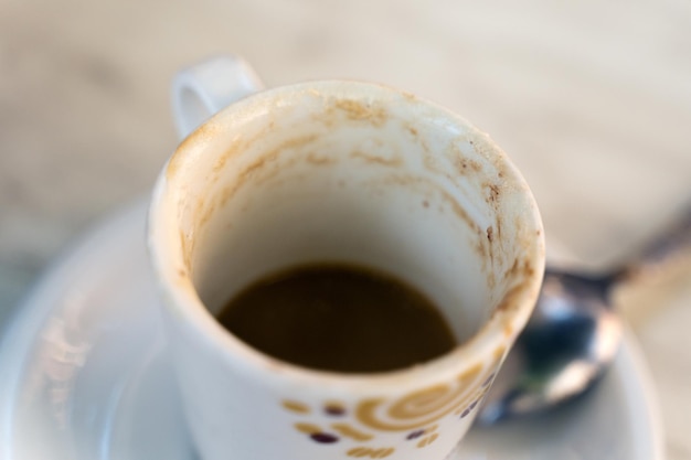 Xícara de café branca fica em pires em mesa de madeira no terraço do café ou restaurante em uma rua da cidade