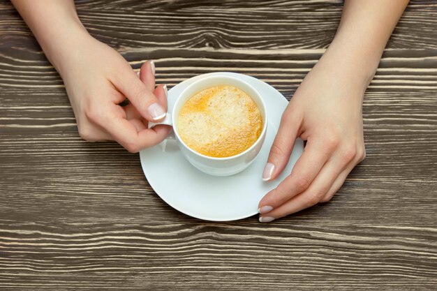 Xícara de café branca na mão feminina