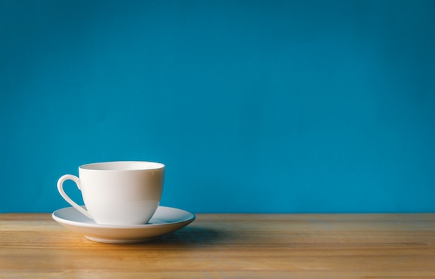 Xícara de café branca na mesa de madeira com fundo azul