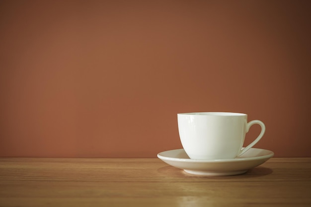 Foto xícara de café branca na mesa de madeira com fundo marrom