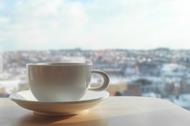 Xícara de café branca na mesa no café no fundo desfocado