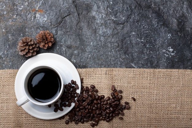 Foto xícara de café branco, pinho seco na serapilheira em pedra preta