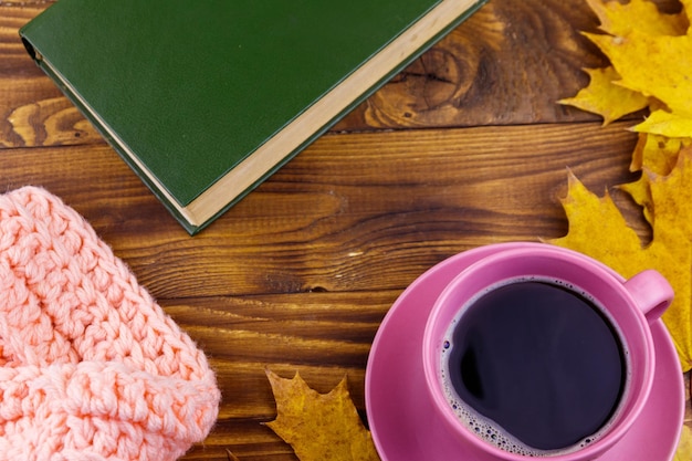Xícara de café, cachecol tricotado e folhas de bordo amarelas na mesa de madeira Outono ainda vida