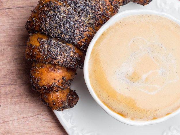 Xícara de café cappuccino e croissant na vista superior da mesa de madeira