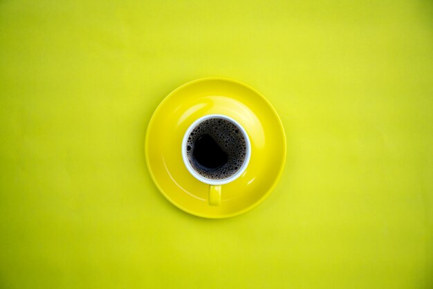 Xícara de café colorida sobre fundo de papel amarelo.