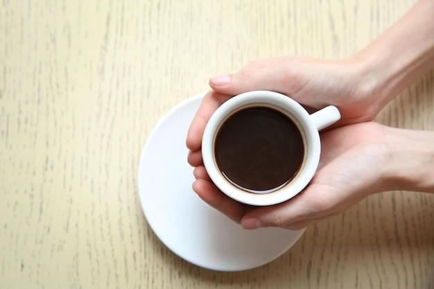 Xícara de café com as mãos no fundo da mesa