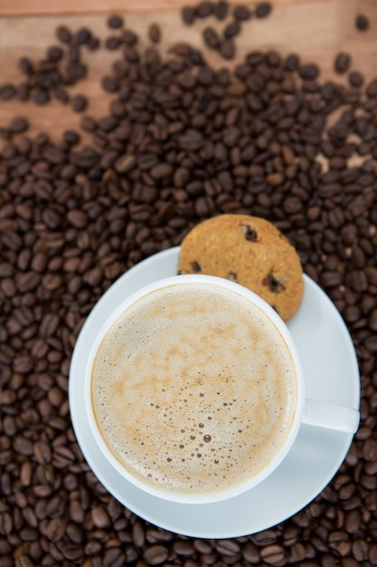 Xícara de café com biscoito e grãos de café