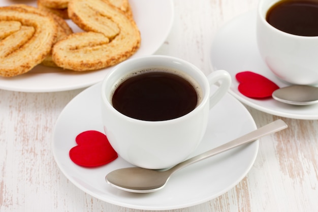 Foto xícara de café com biscoitos e coração vermelho