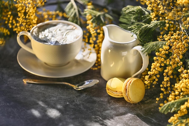 xícara de café com biscoitos e flores amarelas