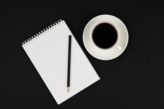 Xícara de café com caderno e lápis preto. Planejador de negócios