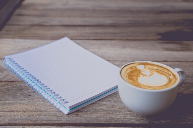 xícara de café com caderno na mesa de madeira