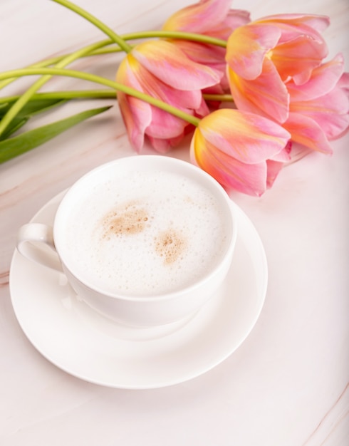 Xícara de café com chocolate e tulipas rosa em fundo de mármore