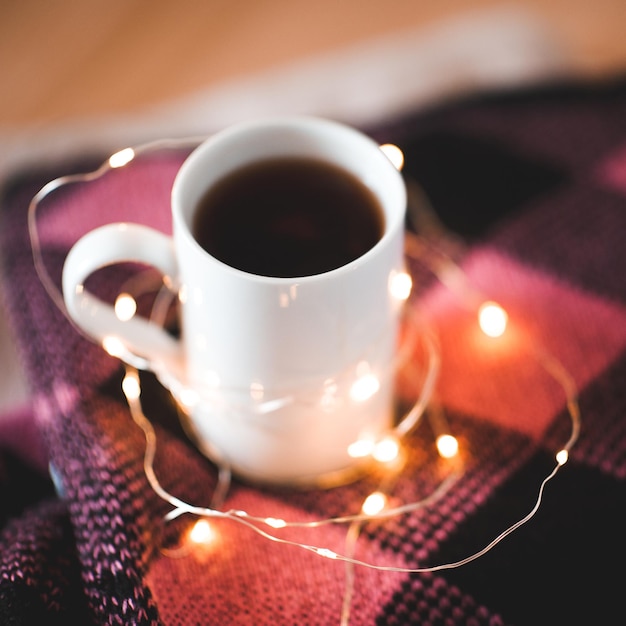 Xícara de café com closeup de luzes de Natal. Inverno.