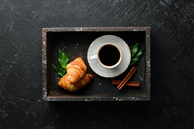 Xícara de café com croissant café da manhã em um fundo de pedra preta vista superior espaço livre para o seu texto