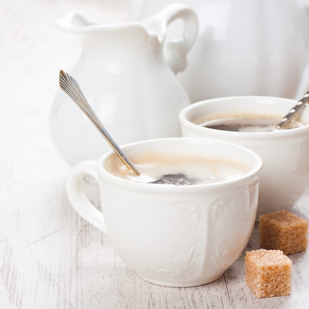 Xícara de café com cubos de açúcar e jarro de leite