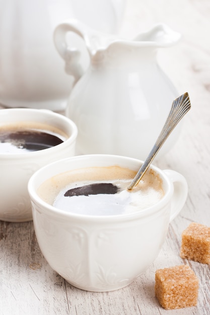 Xícara de café com cubos de açúcar e jarro de leite