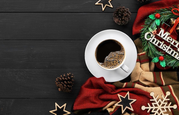 Xícara de café com decorações de natal na mesa de madeira preta vista superior