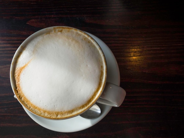 Xícara de café com espuma na vista superior da mesa de madeira