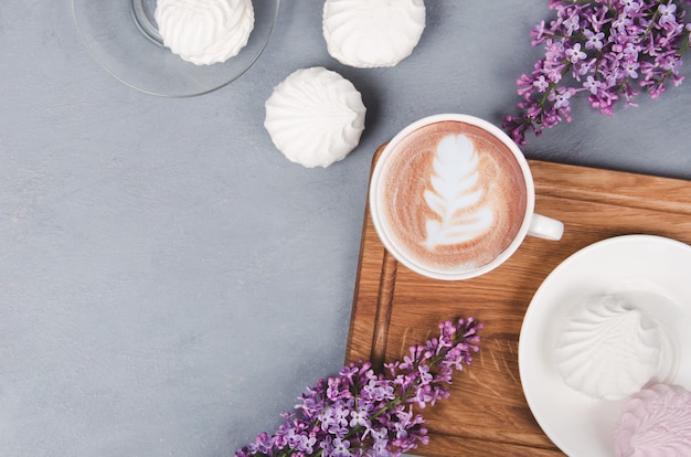 Xícara de café com flores lilás e marshmallows