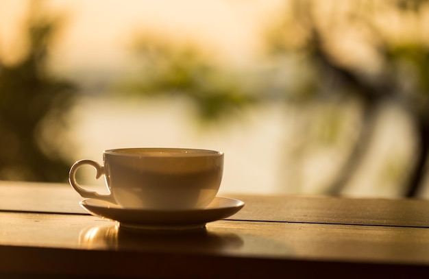 Xícara de café com fundo por do sol na mesa de madeira