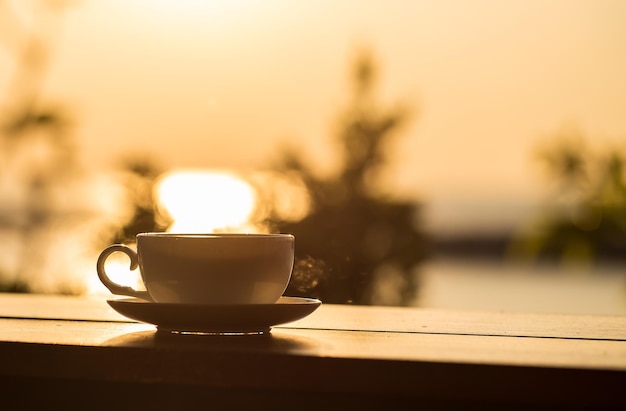 Xícara de café com fundo por do sol na mesa de madeira