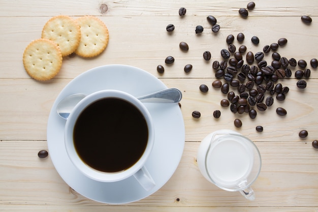 Xícara de café com grão de café e bolacha em madeira