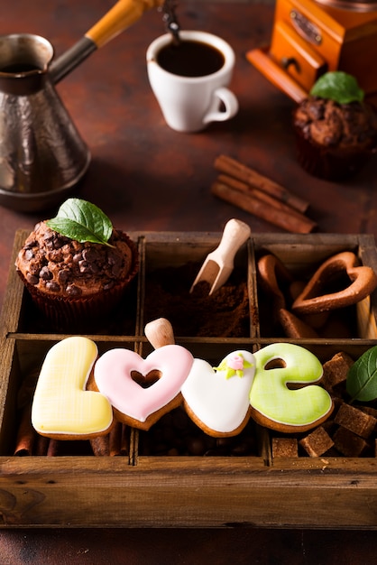 Foto xícara de café com grãos de café, caixa de madeira com grãos de café e especiarias, biscoitos