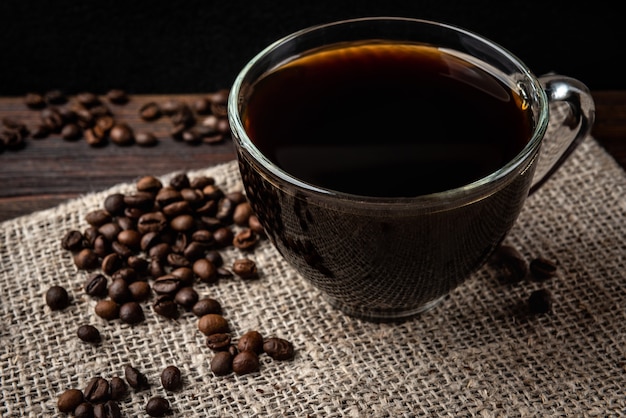 Xícara de café com grãos de café no fundo escuro de madeira.