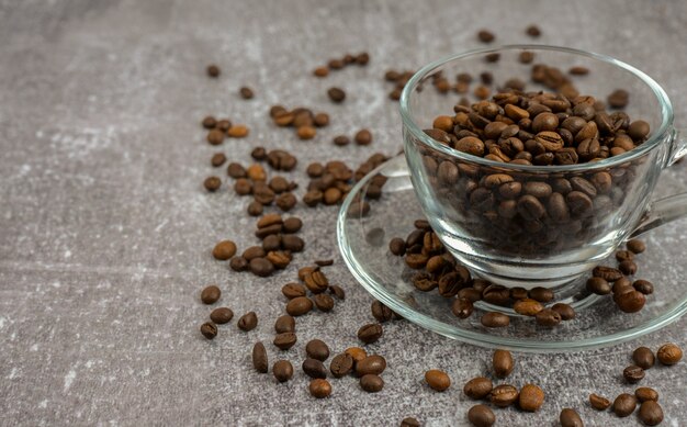 Xícara de café com grãos torrados em fundo cinza pedra com espaço de cópia para o texto