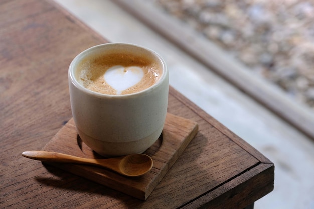 Xícara de café com latte art em formato de coração na mesa de madeira